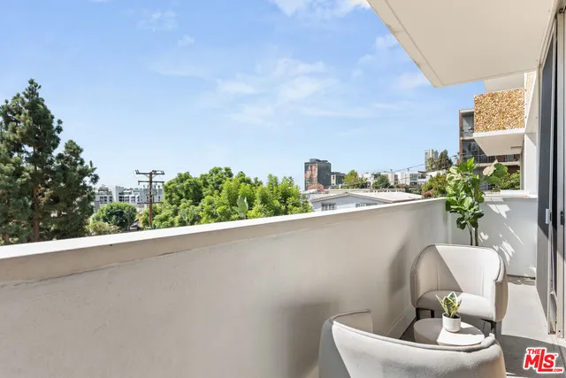 a roof deck with table and chairs and potted plants
