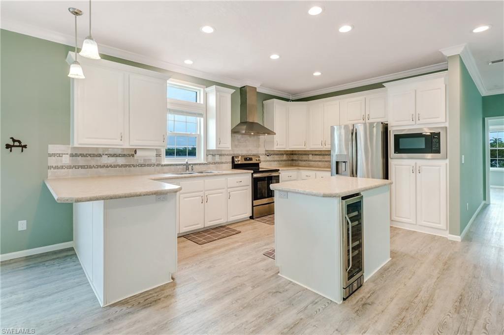 4835 East Riverside Drive Fort Myers, FL 33905 - Photo 13 of 35 a kitchen with stainless steel appliances granite countertop a stove top oven a refrigerator a sink and dishwasher with wooden floor