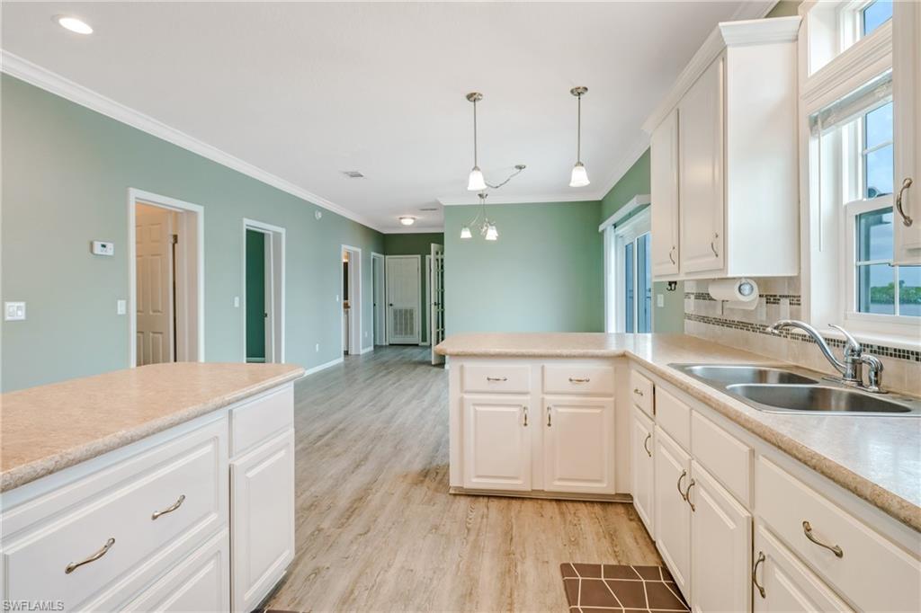 4835 East Riverside Drive Fort Myers, FL 33905 - Photo 16 of 35 a kitchen with granite countertop a sink and white cabinets with wooden floor