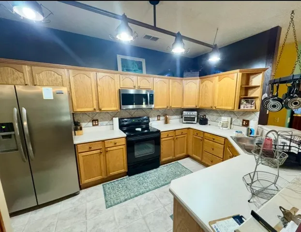 a kitchen with stainless steel appliances granite countertop a sink a stove a refrigerator a washer dryer and a dining table