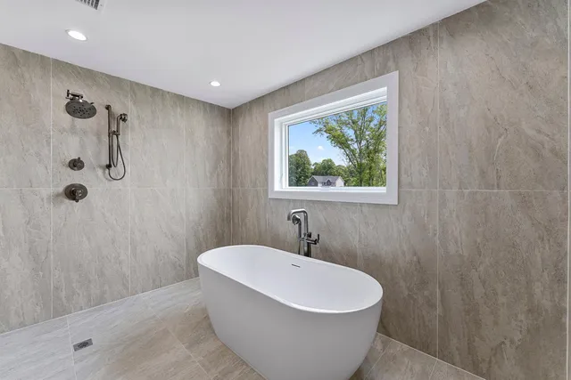 a white bath tub sitting in a bathroom next to a window