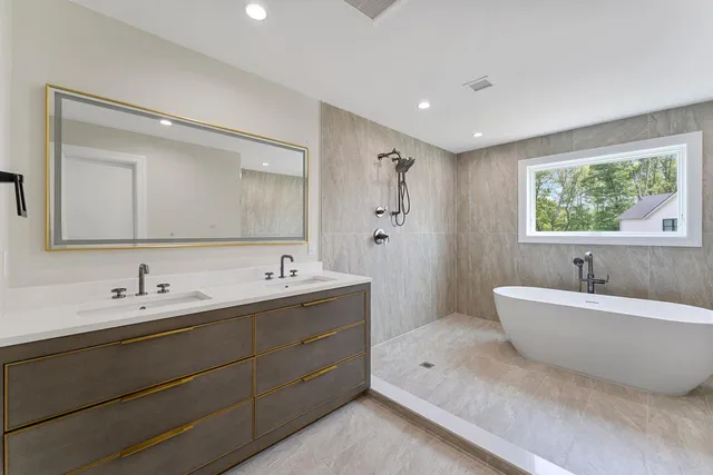 a spacious bathroom with a double vanity sink mirror and bathtub