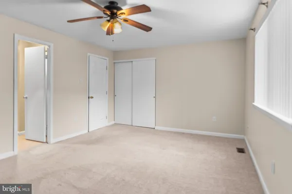 a view of an empty room and window with a chandelier fan