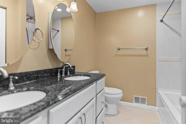 a bathroom with a granite countertop sink a toilet and a mirror