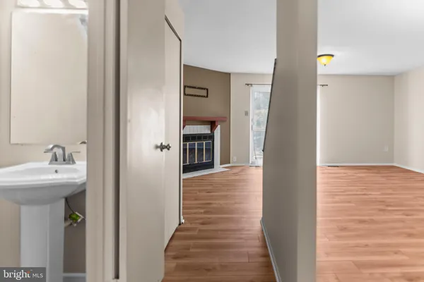 a view of a hallway with wooden floor and a bathroom