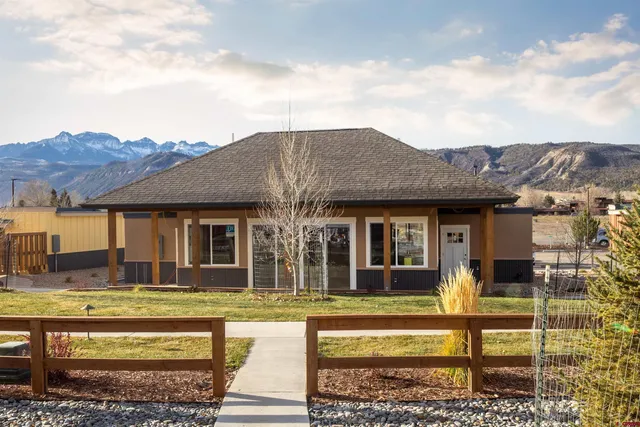 a view of a house with a big yard plants and large tree