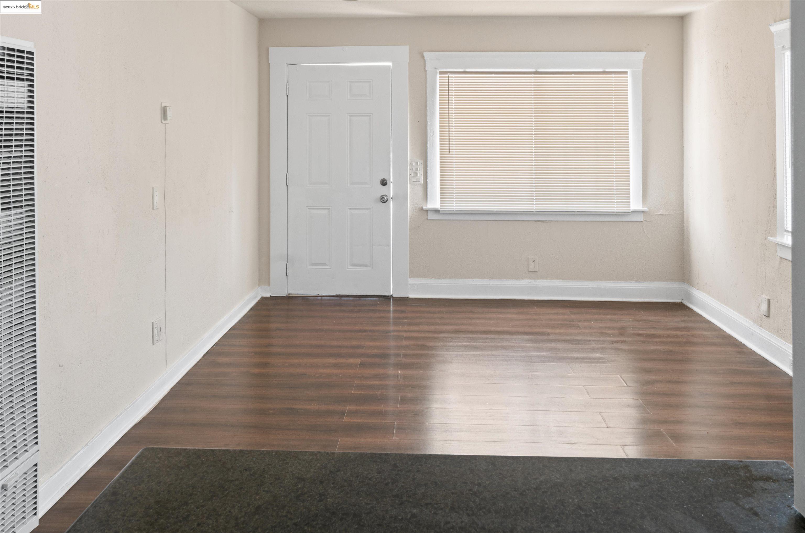 1285 77th Avenue Oakland, CA 94621 - Photo 2 of 8 an empty room with wooden floor and windows