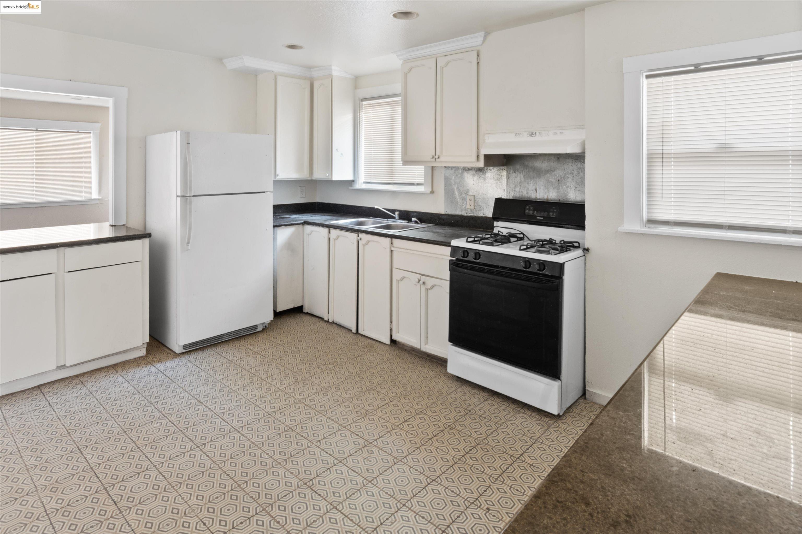 1285 77th Avenue Oakland, CA 94621 - Photo 3 of 8 a kitchen with white cabinets and white appliances