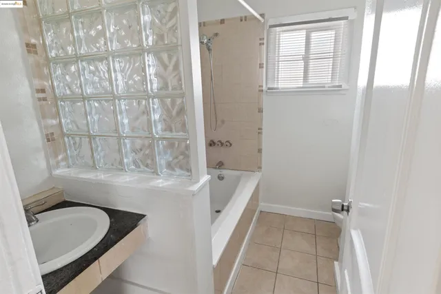 a bathroom with a granite countertop sink and a bathtub