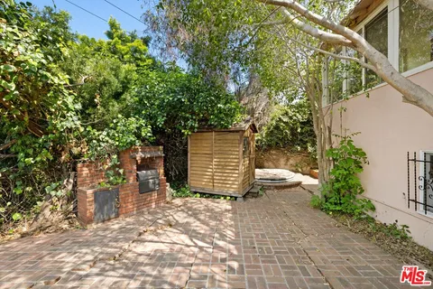 a view of a backyard with plants and large tree