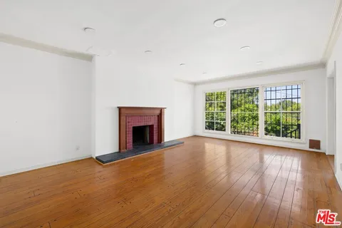a view of empty room with wooden floor and fireplace
