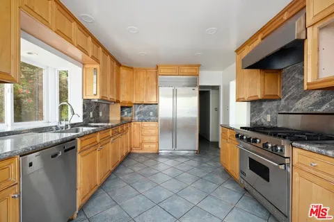 a large kitchen with stainless steel appliances granite countertop a stove a sink and a refrigerator