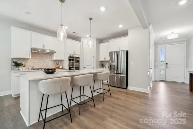 a kitchen with stainless steel appliances a table chairs refrigerator and microwave