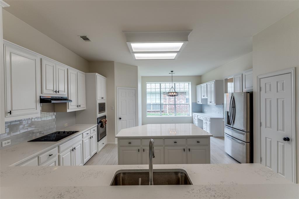 3313 Shady Valley Road Plano, TX 75025 - Photo 16 of 34 a kitchen with a refrigerator and white cabinets