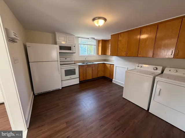 a kitchen with a refrigerator a sink and wooden floor