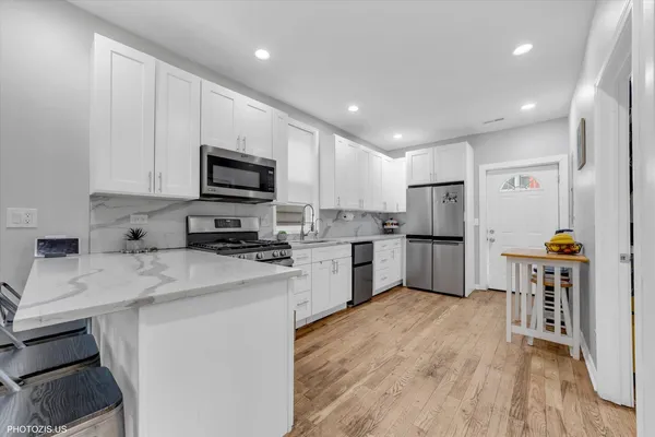 a kitchen with granite countertop a refrigerator a stove top oven a sink dishwasher and white cabinets with wooden floor