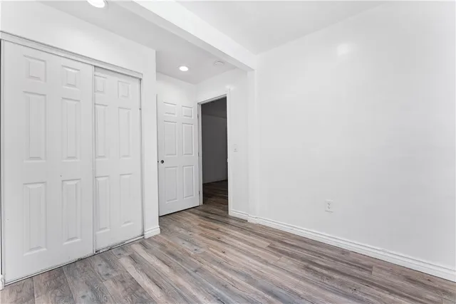 a view of an empty room with closet and wooden floor