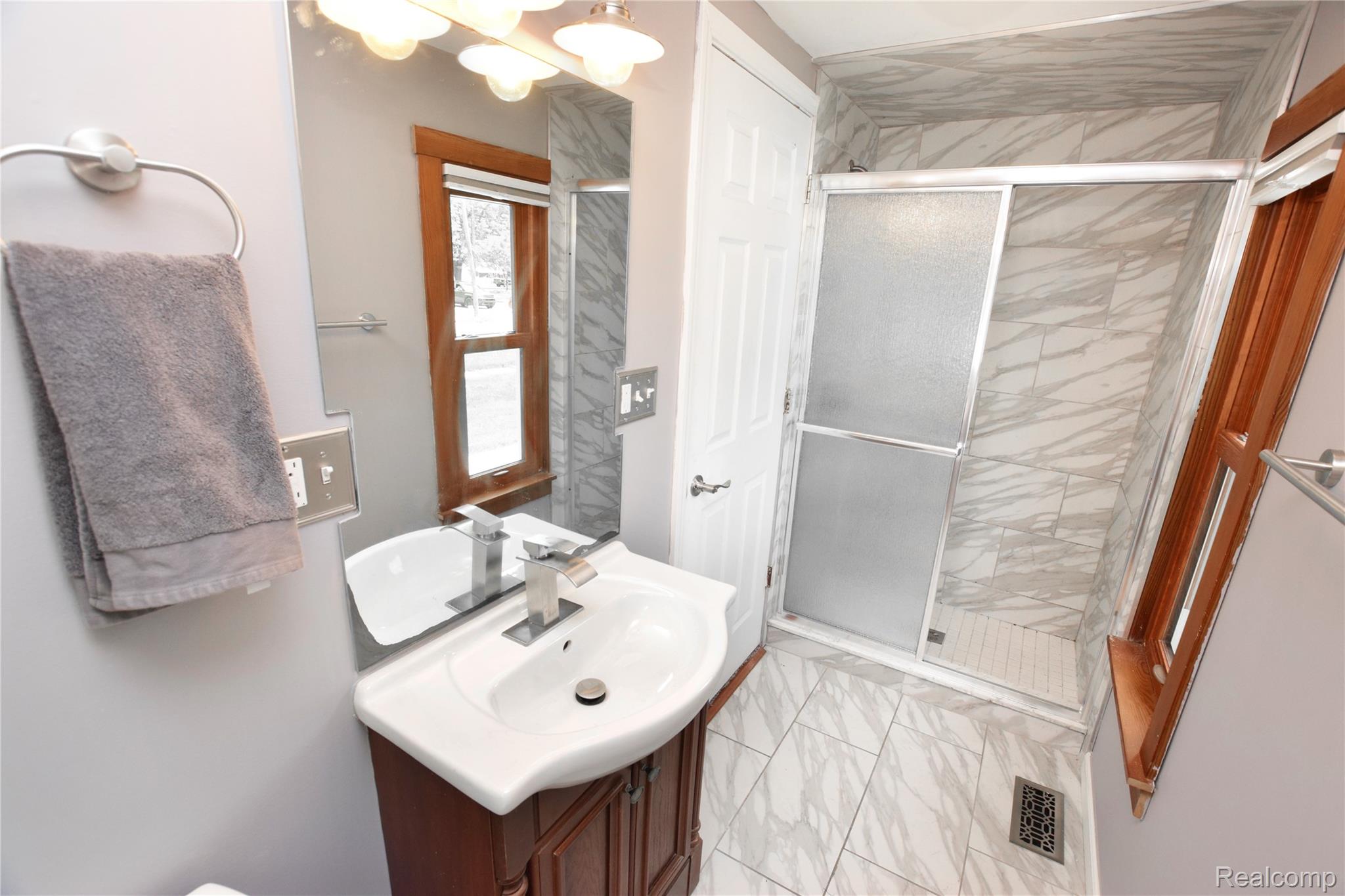404 North Adelaide Street Fenton, MI 48430 - Photo 9 of 23 Bathroom featuring a shower with sliding frosted glass doors, white subway tile shower pan, and marble-look wall tile