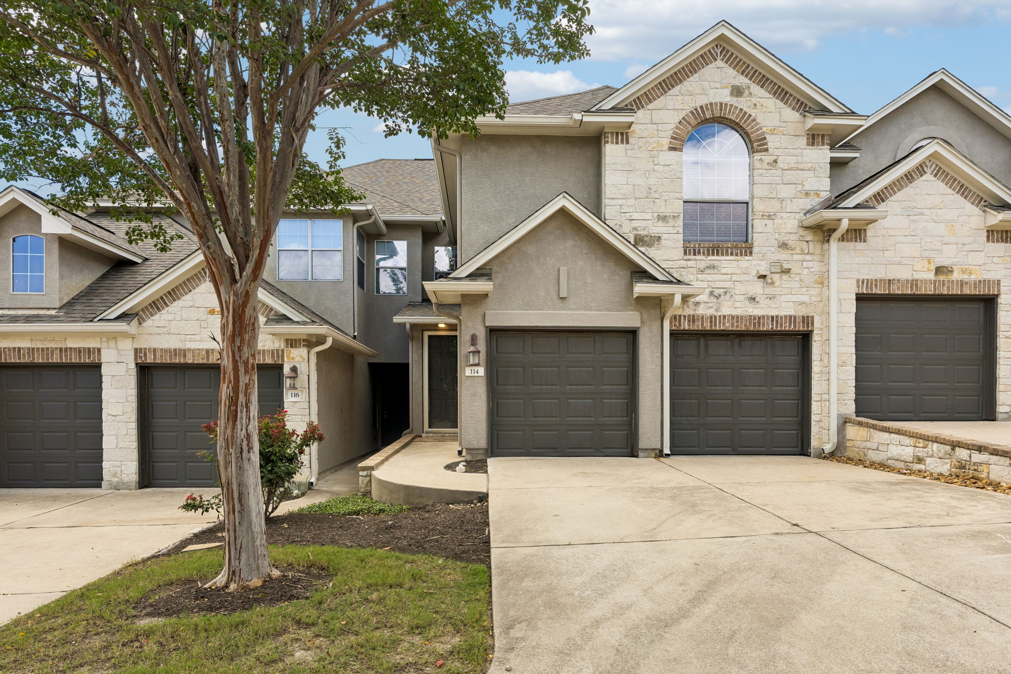 A well-maintained facade with varied stone and stucco finishes enhances this inviting townhome's curb appeal.