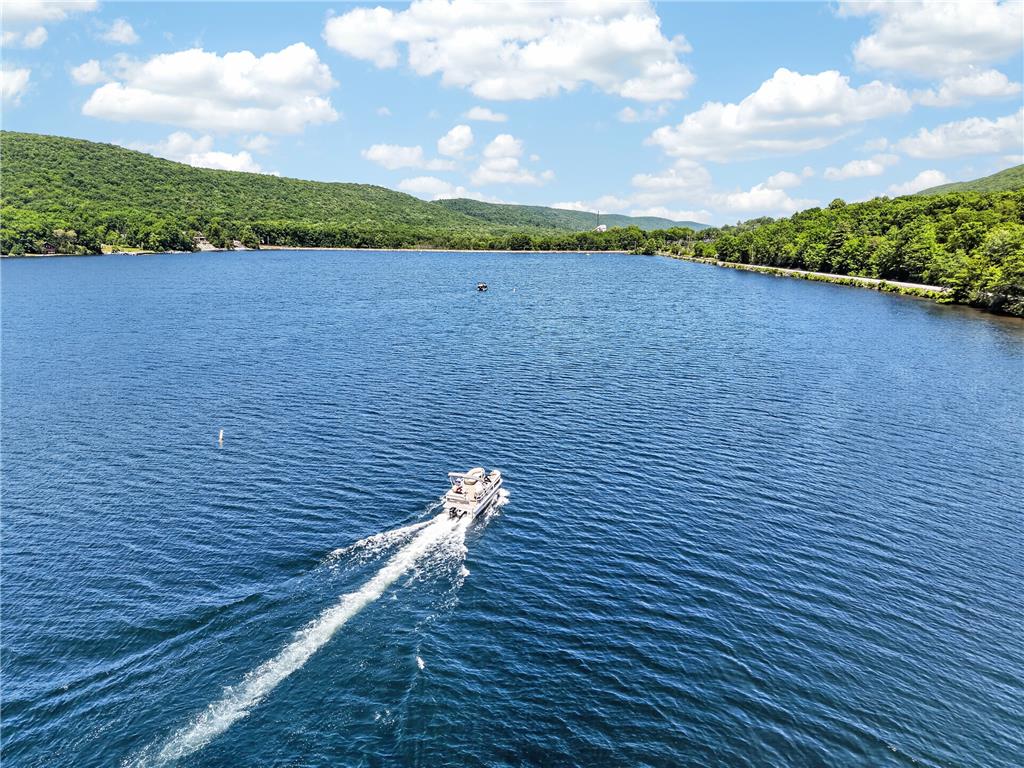 18 White Oak Road Nesquehoning, PA 18240 - Photo 9 of 52 A boat cruises across the serene lake, enveloped by verdant hills under a vast sky.