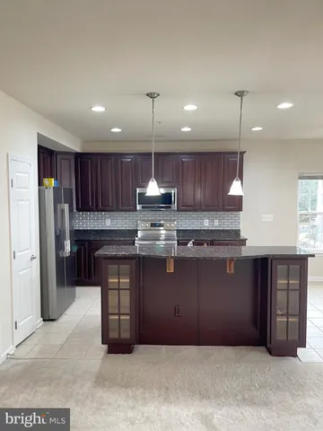 a kitchen with stainless steel appliances granite countertop a refrigerator a sink a stove a microwave and wooden cabinets