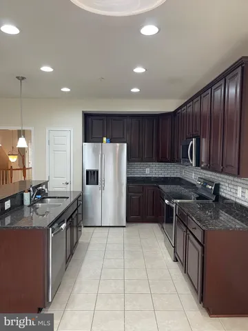a kitchen with granite countertop a sink a counter top space a stove and cabinets