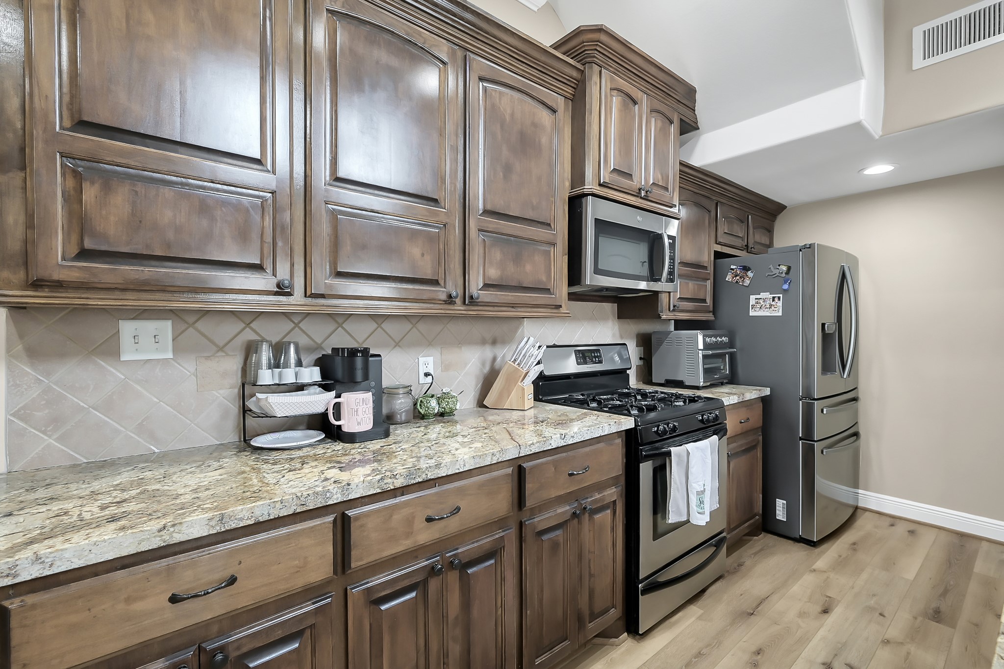 113 Capetown Way Montgomery, TX 77356 - Photo 11 of 39 a kitchen with stainless steel appliances granite countertop a refrigerator a stove and a sink with wooden floor