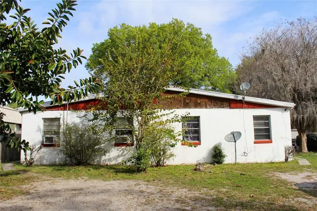 a view of a white house with a big yard and large tree