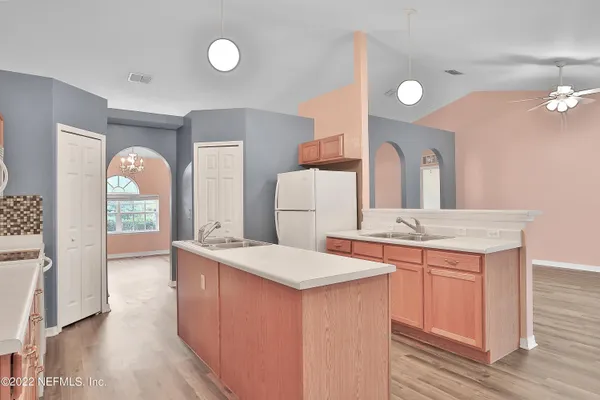 a large kitchen with a sink and wooden floor