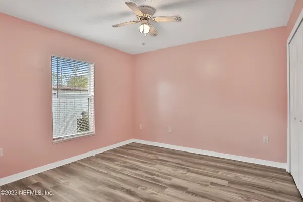 an empty room with a window and a ceiling fan