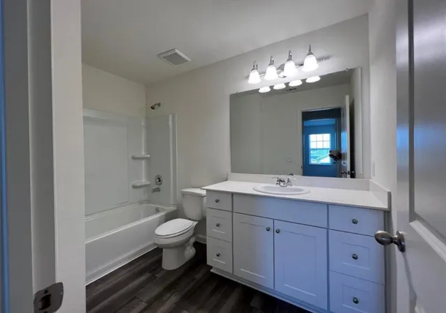 a bathroom with a double vanity sink toilet mirror and bathtub