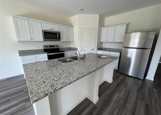 a kitchen with granite countertop a refrigerator stove and microwave
