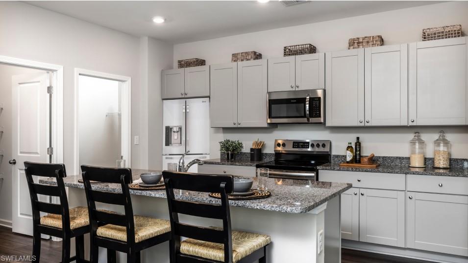 12240 Dakota Ridge Place North Fort Myers, FL 33917 - Photo 6 of 32 a kitchen with stainless steel appliances granite countertop a stove a sink a dining table and chairs