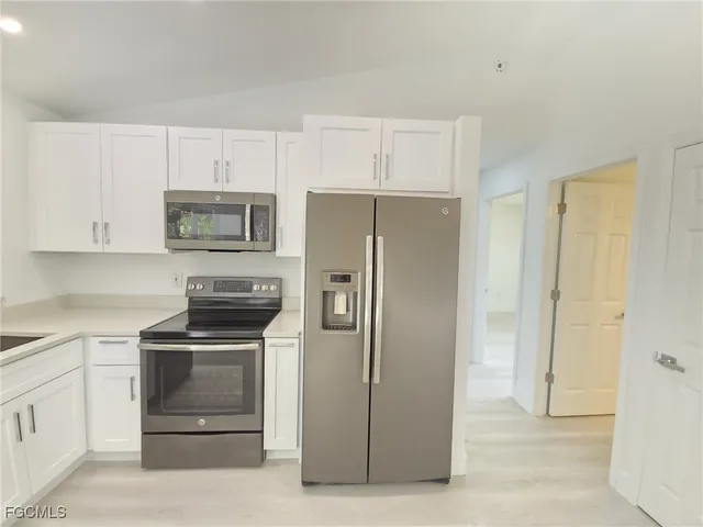 a kitchen with white cabinets and stainless steel appliances
