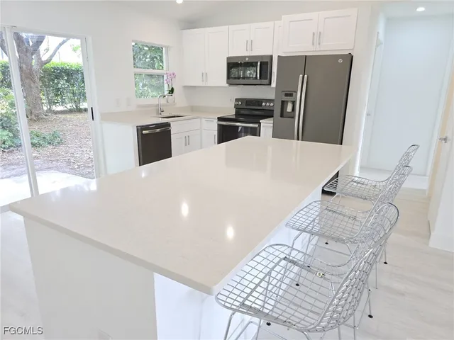a kitchen with stainless steel appliances kitchen island granite countertop a refrigerator a stove a sink and dishwasher