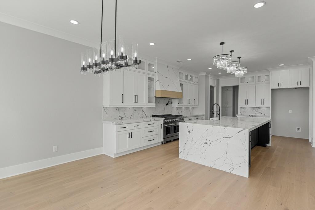 2739 South Waterworks Road Buford, GA 30518 - Photo 25 of 62 a large white kitchen with a refrigerator a stove top oven a sink dishwasher and a dining table with wooden floor