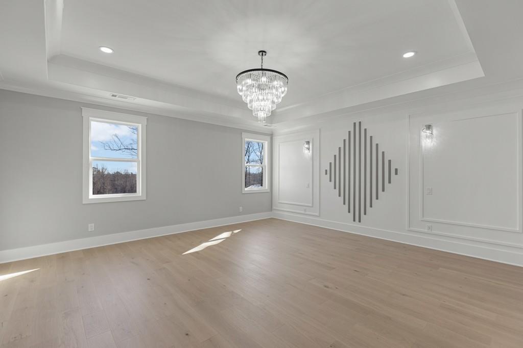 2739 South Waterworks Road Buford, GA 30518 - Photo 49 of 62 an empty room with wooden floor chandelier and windows