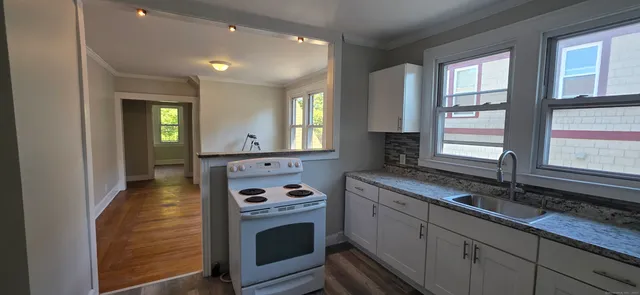 an empty room with wooden floor cabinet and windows