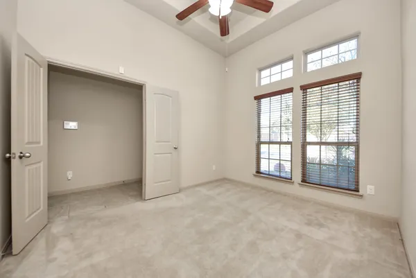 an empty room with chandelier fan and windows