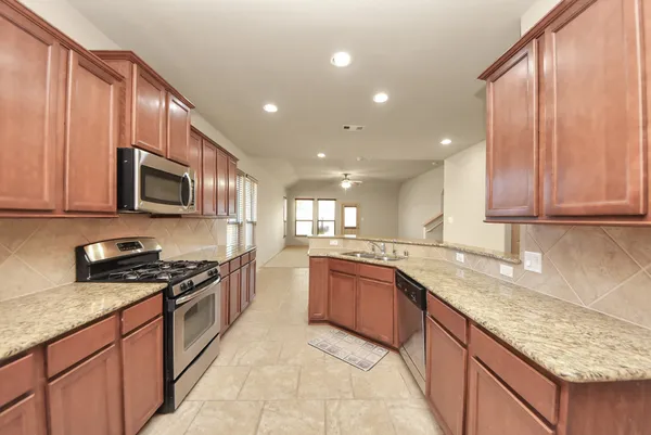 a kitchen with stainless steel appliances granite countertop wooden cabinets granite counter tops and a stove