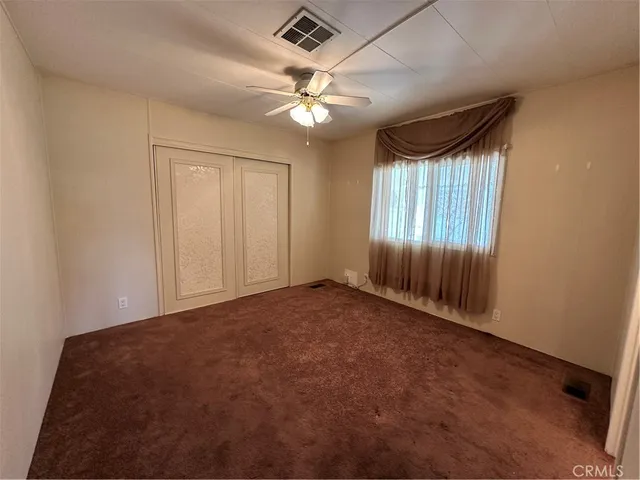 en empty room with windows and ceiling fan