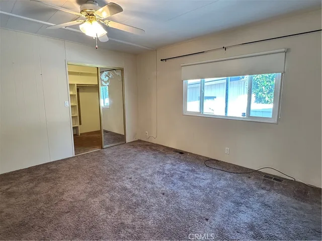 an empty room with a chandelier fan and windows