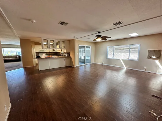 an open kitchen with white cabinets and wooden floor