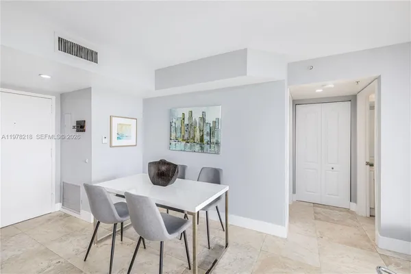 a kitchen with stainless steel appliances kitchen island a table chairs and a refrigerator