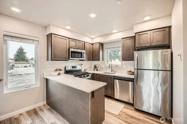 a kitchen with a refrigerator a sink cabinets and wooden floor