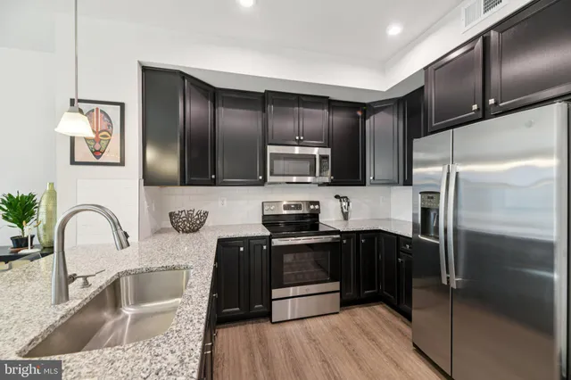 a kitchen with granite countertop a refrigerator and a sink
