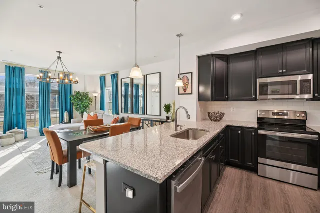 a kitchen with stainless steel appliances granite countertop a stove a kitchen island a sink dishwasher a dining table and chairs with wooden floor