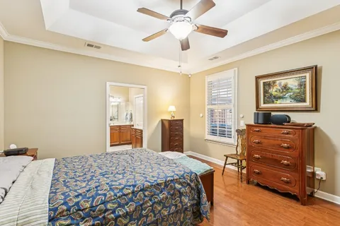 a bedroom with a bed dresser and wooden floor