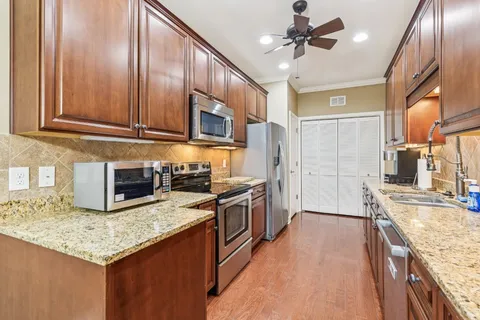 a kitchen with stainless steel appliances granite countertop a sink a stove and a wooden cabinets
