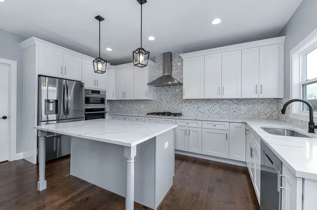 a kitchen with stainless steel appliances granite countertop a sink a stove a refrigerator and island with wooden floor